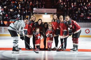 Several people stand on the ice for a ceremonial faceoff.