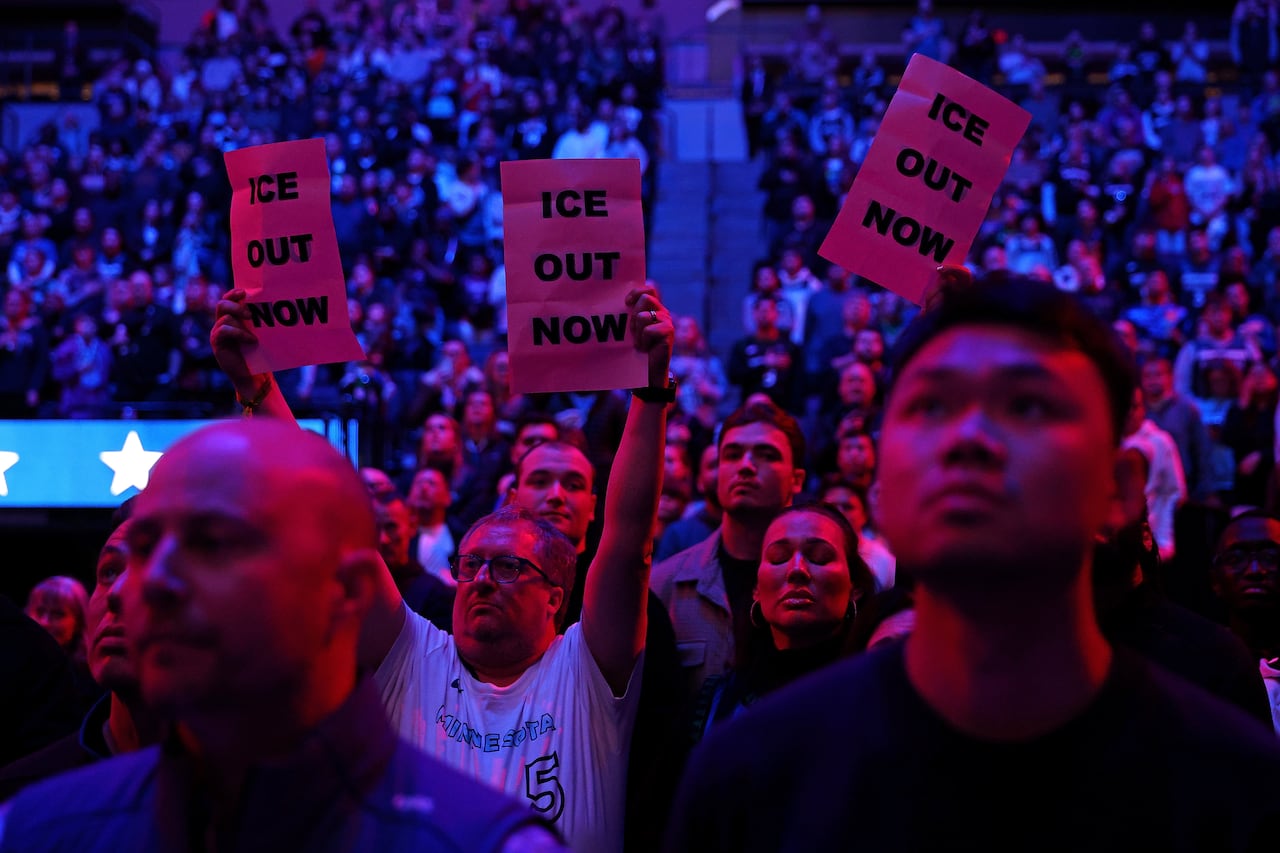 People hold up signs reading, 'Ice out,' during a sports game.