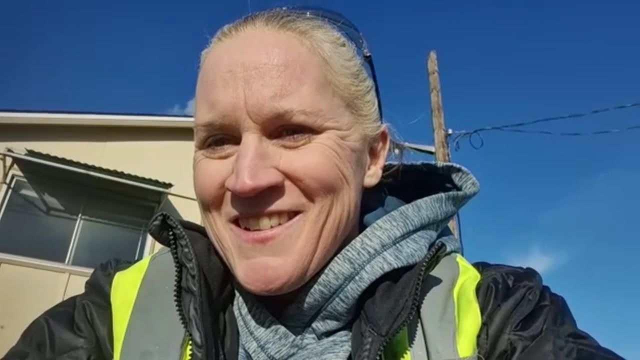 A smiling woman with gray hair and a yellow safety vest 