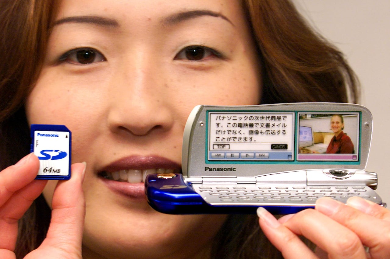 A woman holds up a PDA gadget in the year 2000