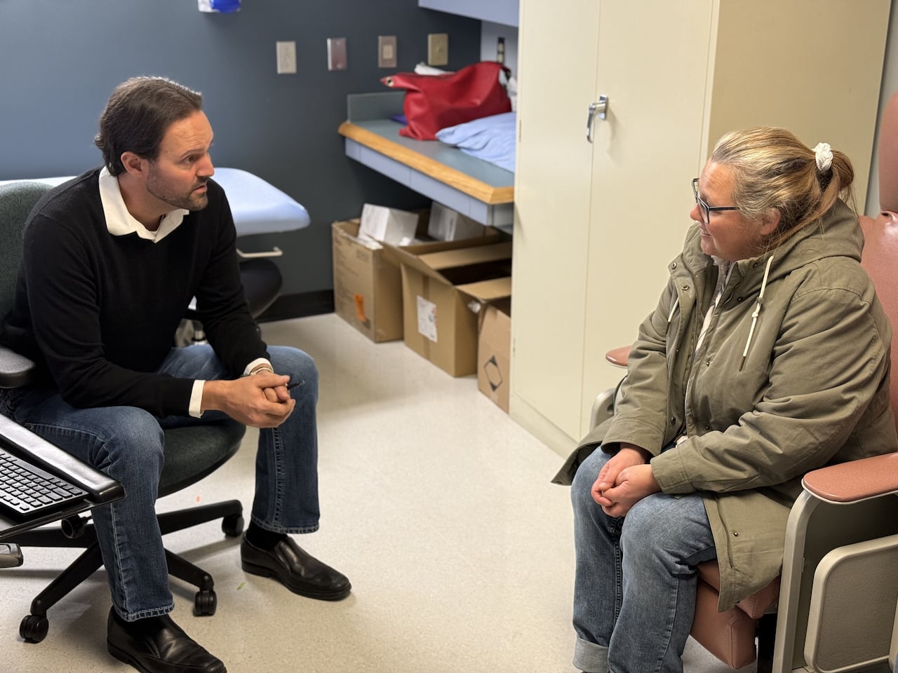 A man speaks to a woman in a medical clinic office.