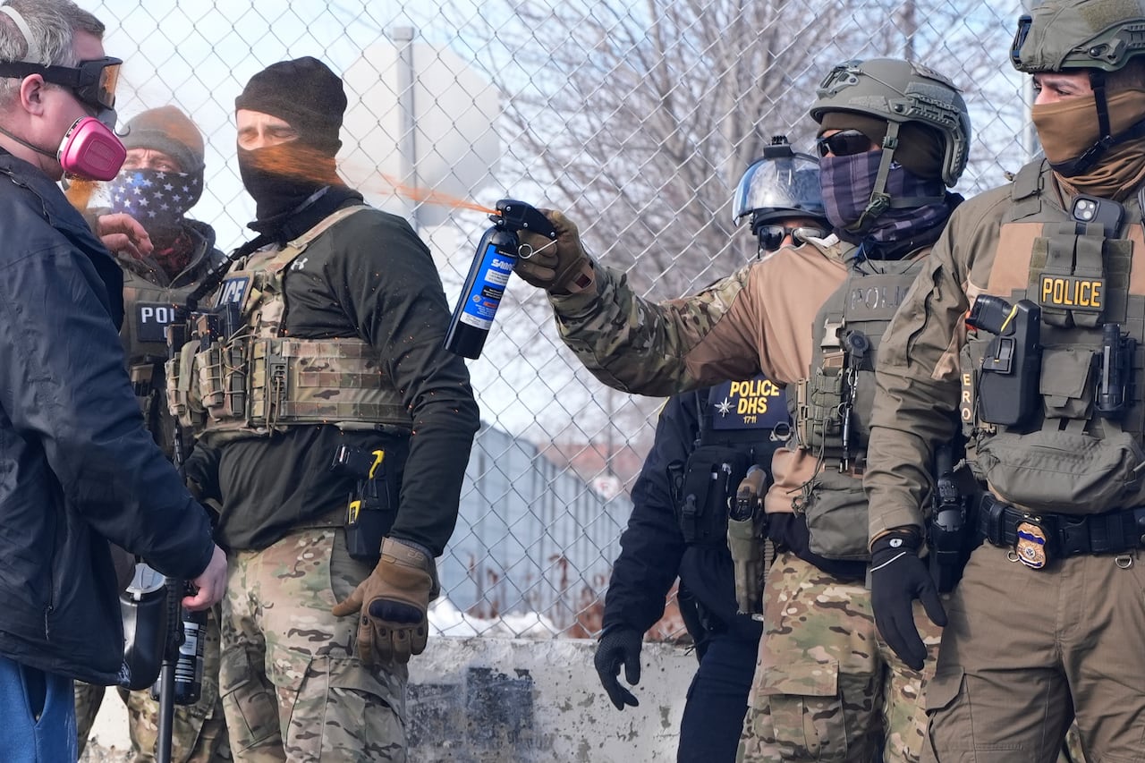 An Immigration and Customs Enforcement (ICE) agent shoots pepper spray at a protester outside of the Bishop Whipple Federal Building, Monday, Jan. 12, 2026, in Minneapolis. (AP Photo/Jen Golbeck)