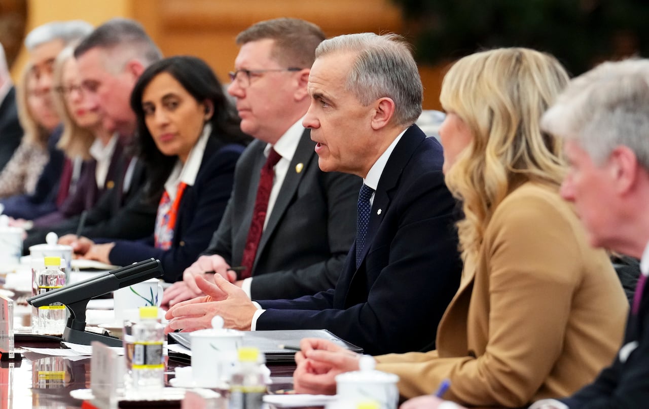 A group of senior officials from Canada sit at a long table