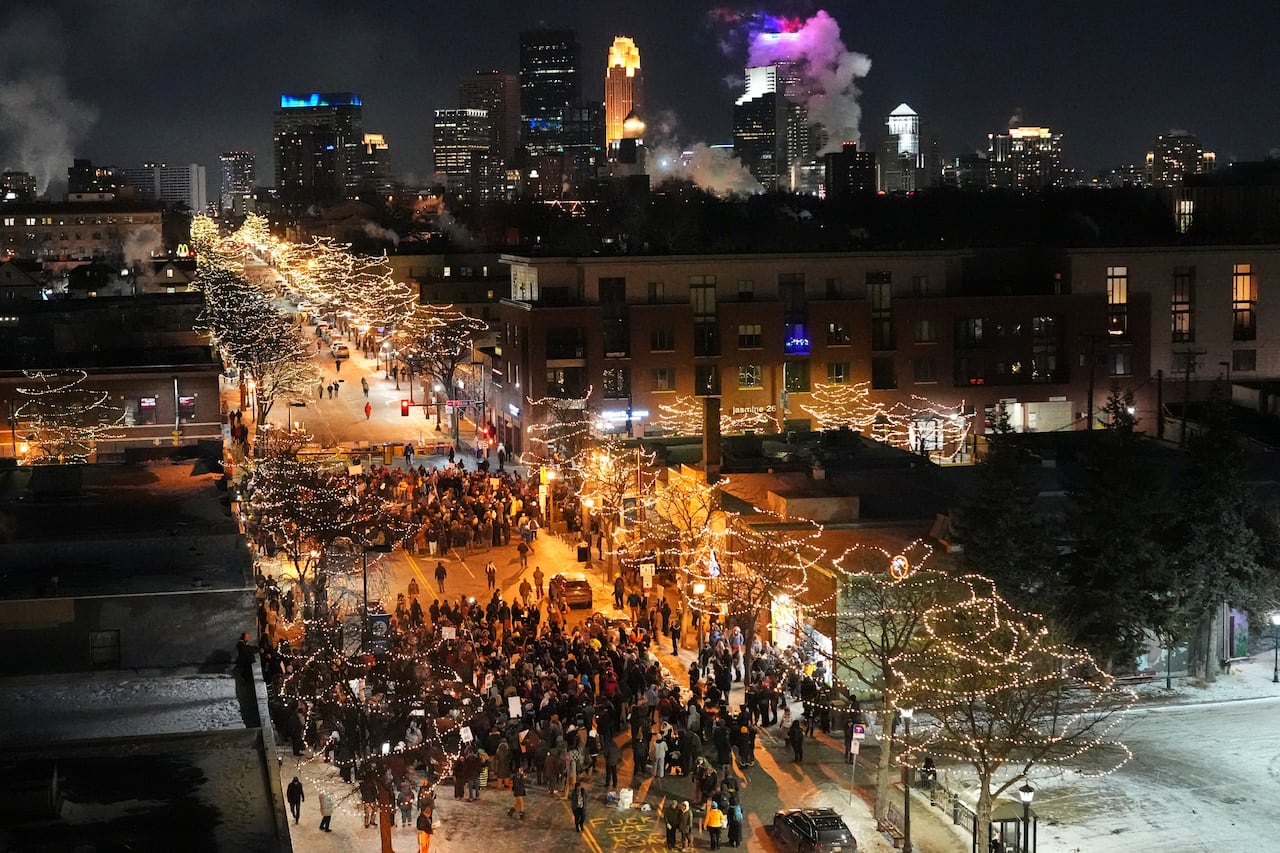 Crowds fill a long city street seen from above on wintry night.